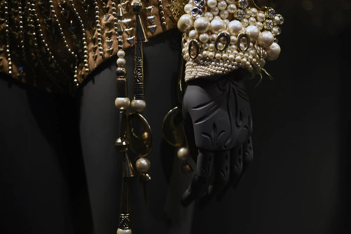 Close-up of jewelry on a mannequin with hand-carved hands on a black background.