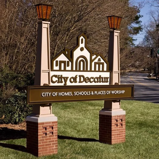 Sign for the city of Decatur with a silhouette of a church and two lamp posts.