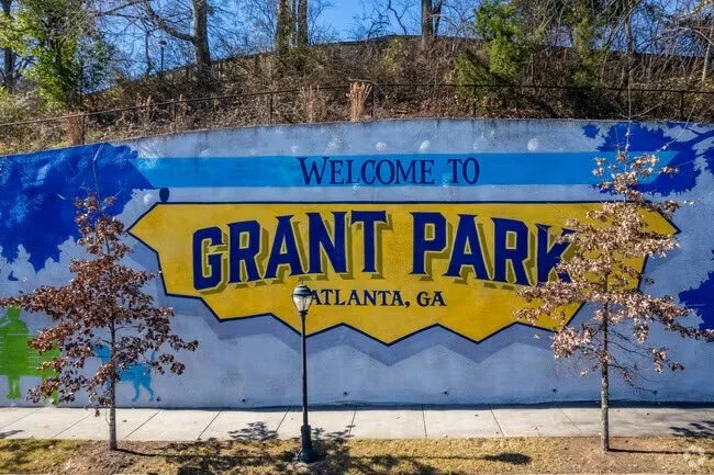 Colorful mural on a wall with the text 'Welcome to Grant Park, Atlanta, GA,' surrounded by trees and a lamppost.