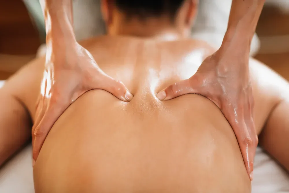 Massage therapist's hands gliding down client's back to relax muscles.