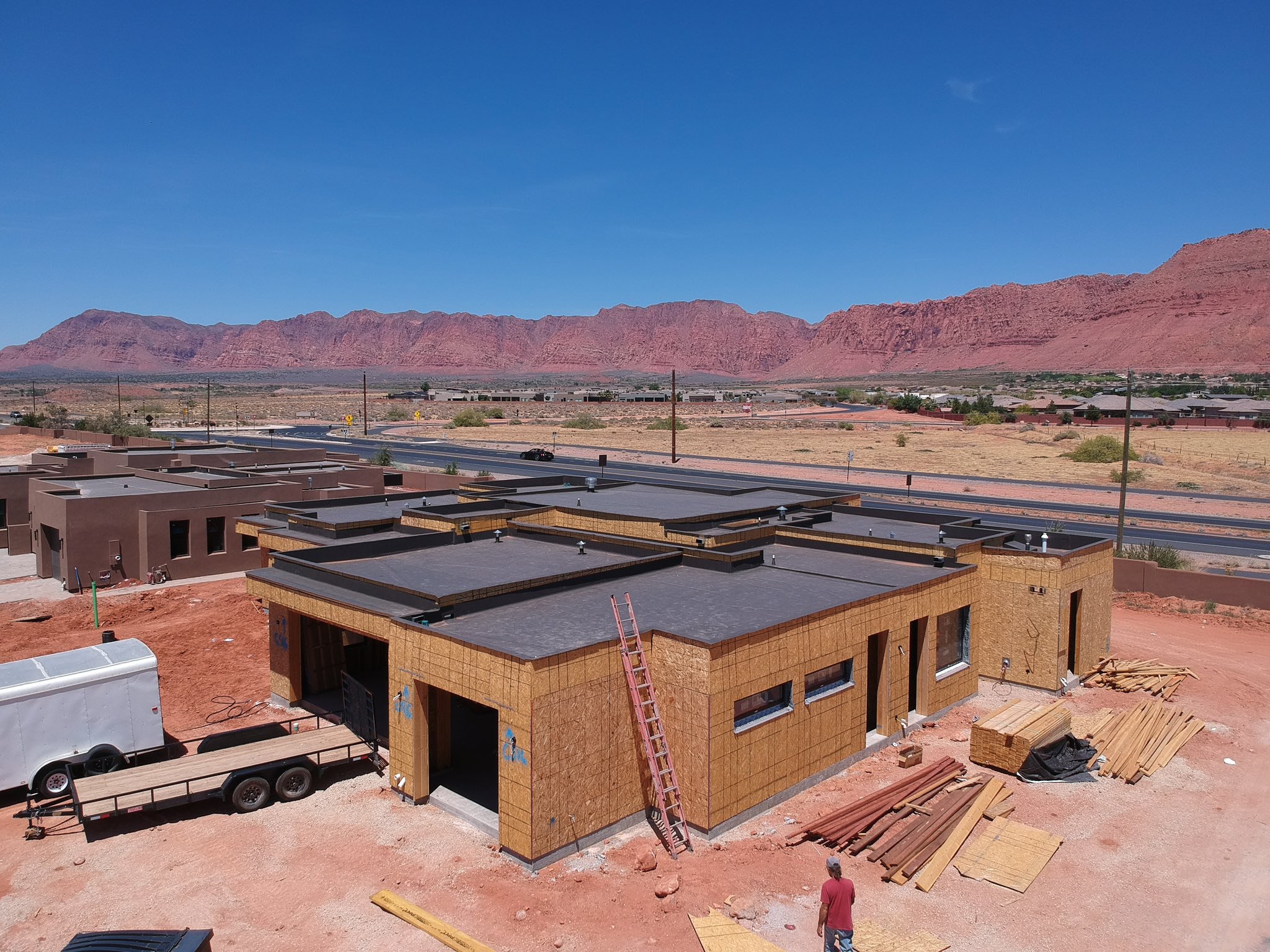 Construcción de casas nuevas en un vecindario en un área desértica con montañas rojas al fondo.