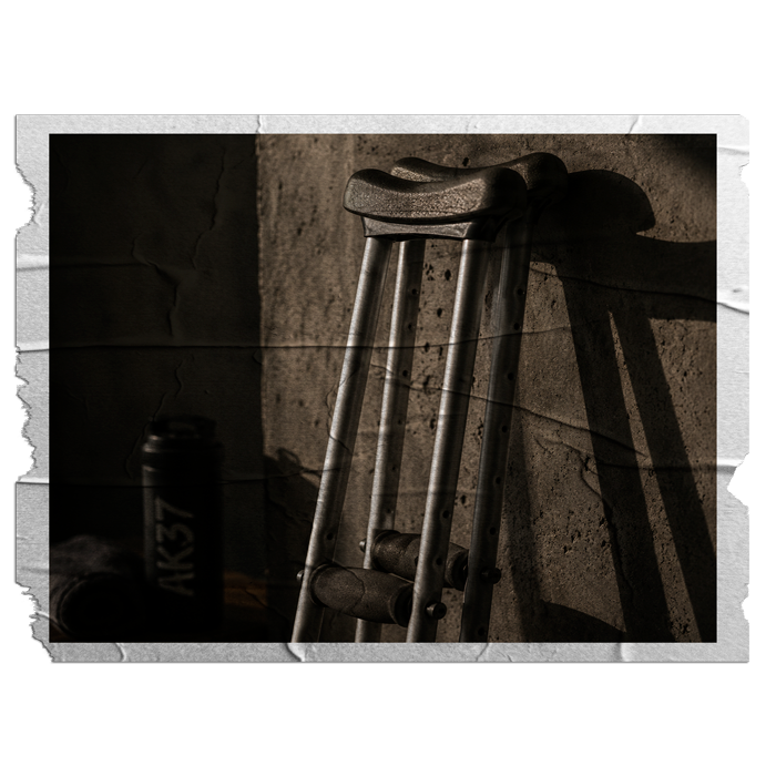 A wooden crutch leaning against a rough wall with a shadow cast beside it.