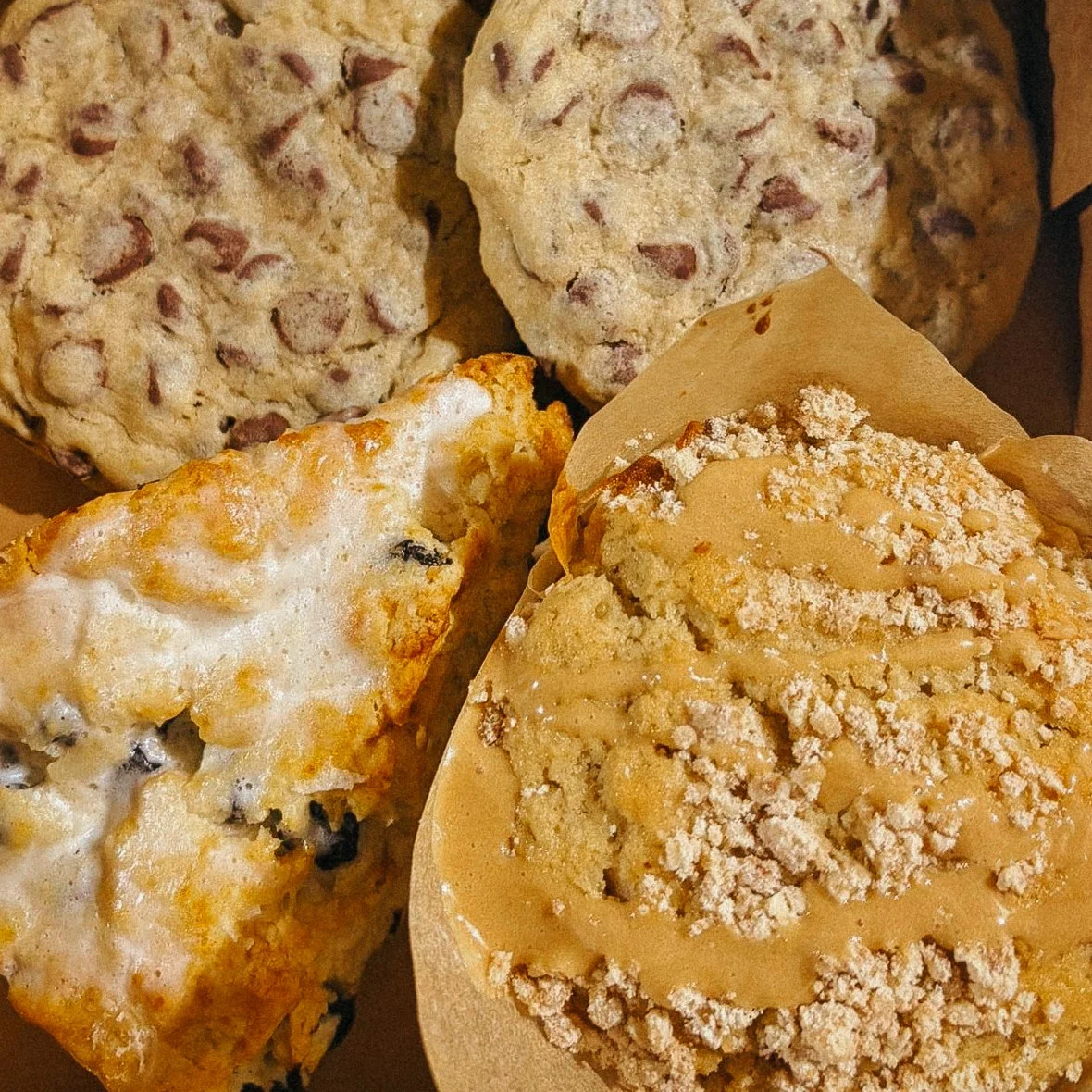 Close-up of assorted baked goods including cookie and cream cookies, a cookie bar with icing, and a crumb-topped bar with frosting.