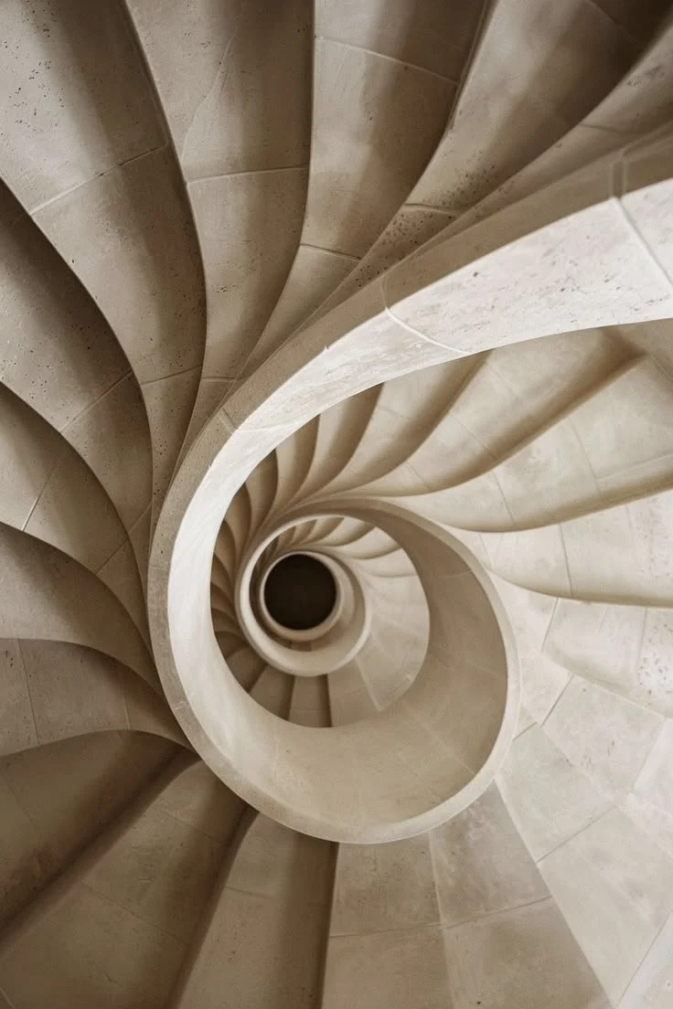 A spiral staircase viewed from the top, showing the curved steps and central hole.