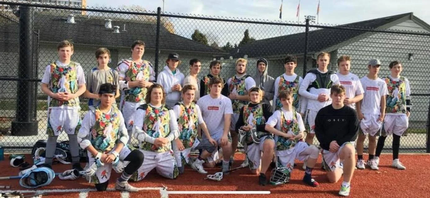 Lacrosse players in colorful jerseys and white shorts posing together on an outdoor court.