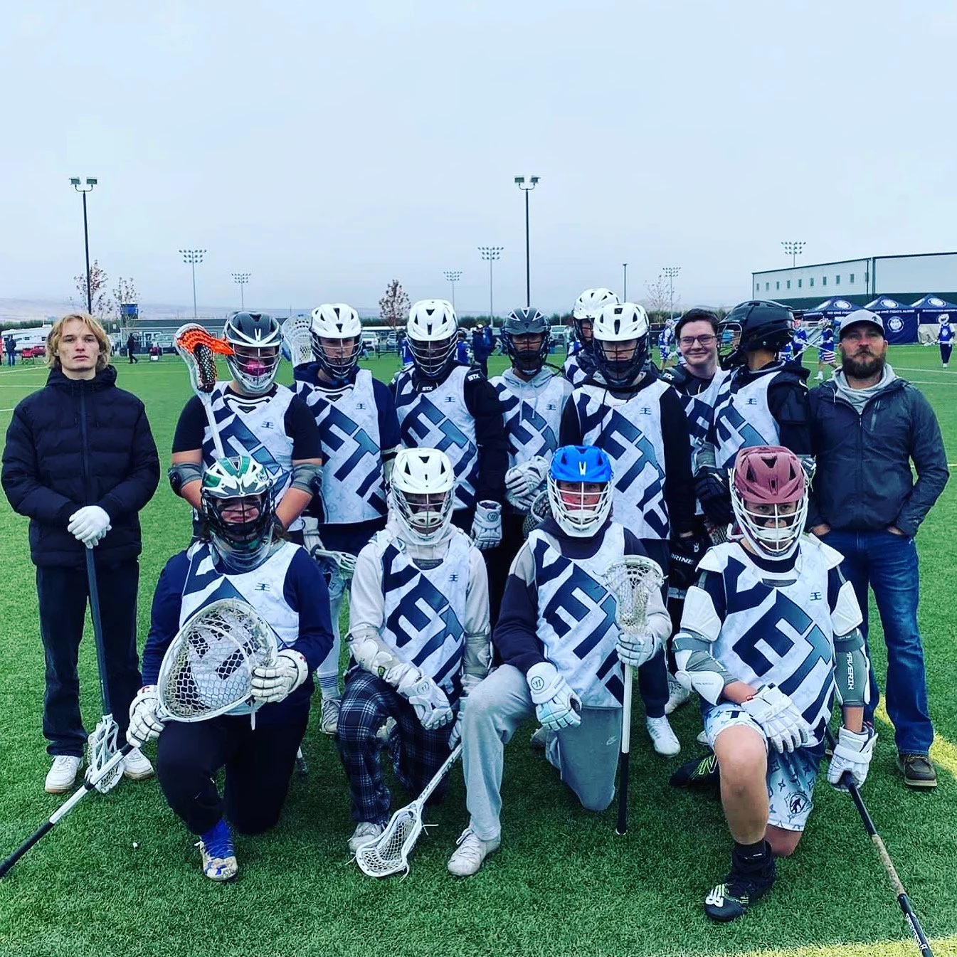 Yetis lacrosse players and coaches posing together on an outdoor field.