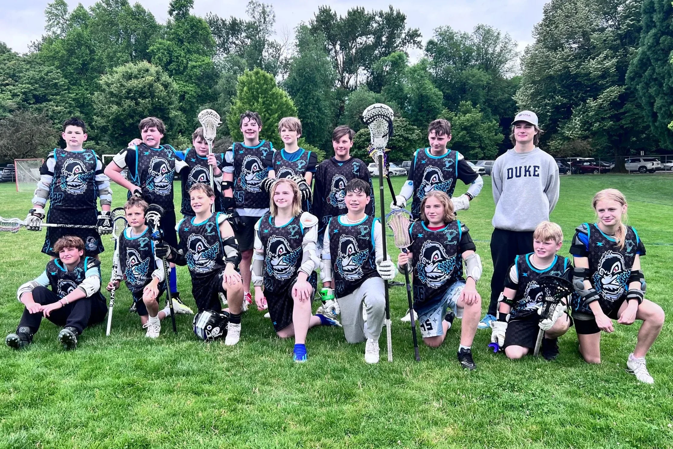 Young Yetis lacrosse players and coach posing together on an outdoor field.