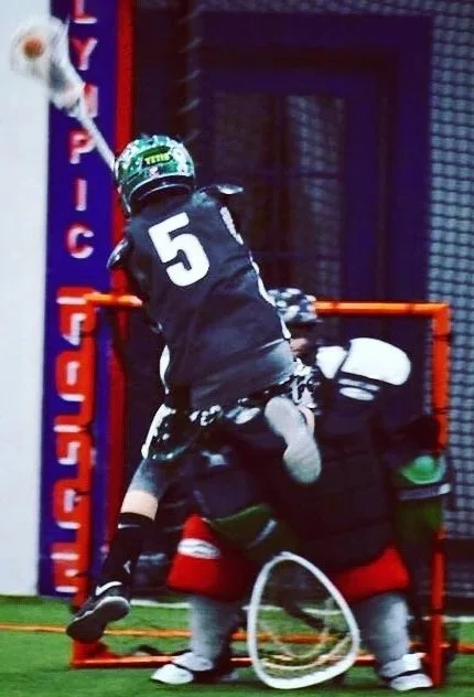 Box lacrosse player attacking the goal during an indoor game.