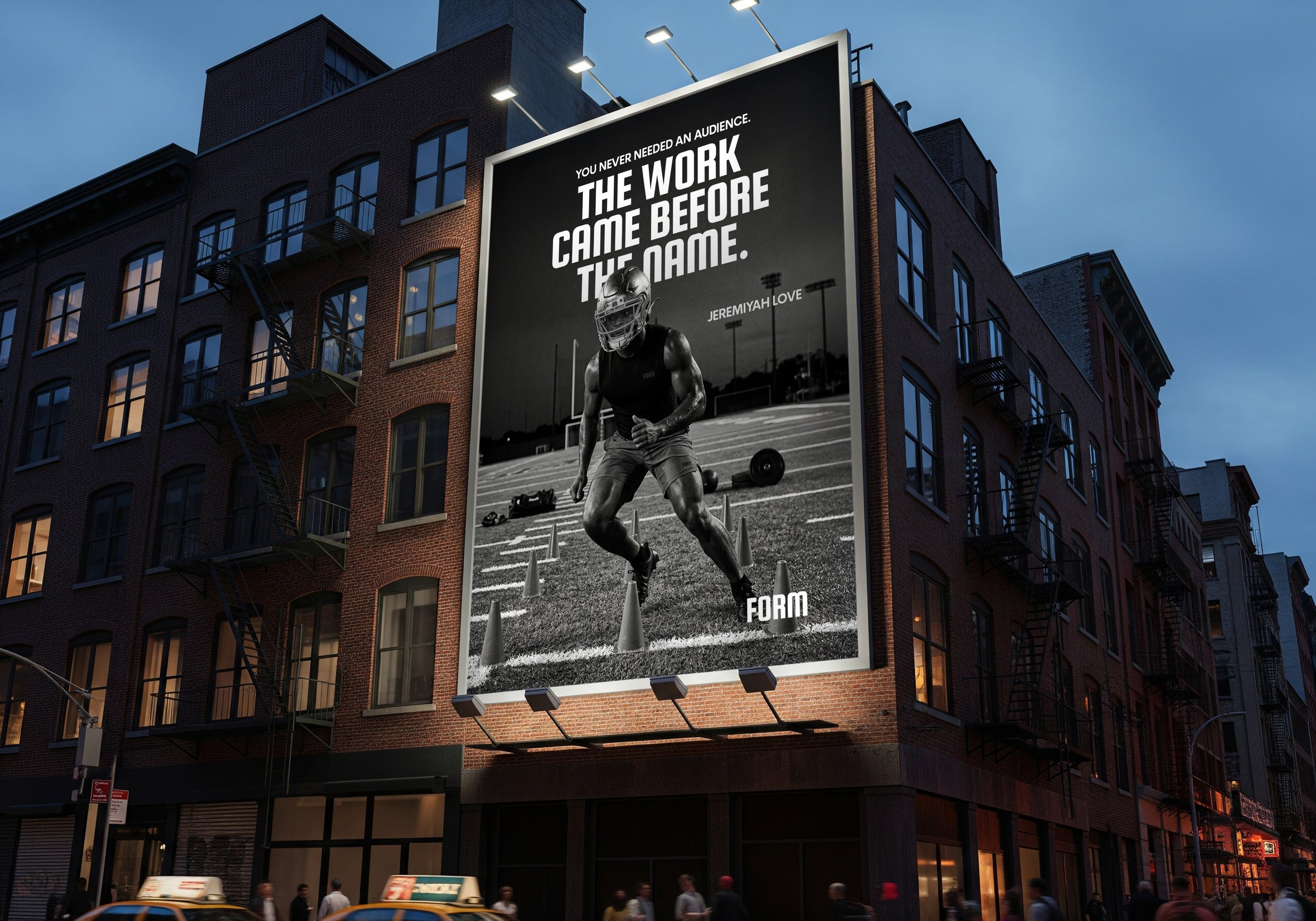 Large billboard on a city building featuring a muscular football player in helmet and athletic clothing running through cones on a track, with the text 'You never needed an audience. The work came before the fame.' and the name 'Jeremiyah Love' at the bottom.
