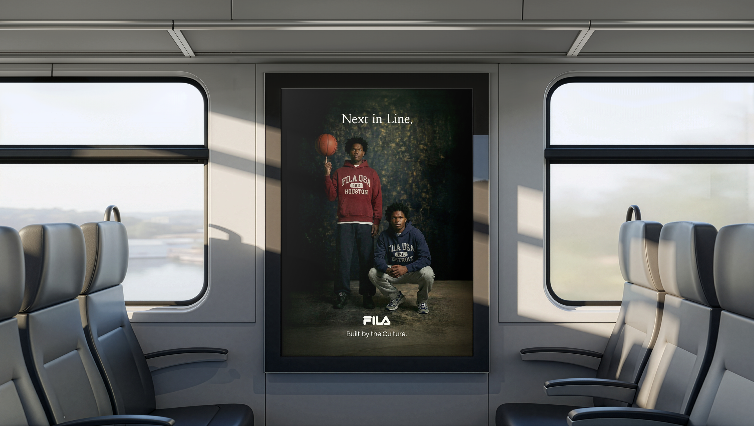 Advertising poster in train showing two young men, one holding a basketball, wearing casual clothing with brands Fila USA, with the text 'Next in Line' and 'Built by the Culture'.