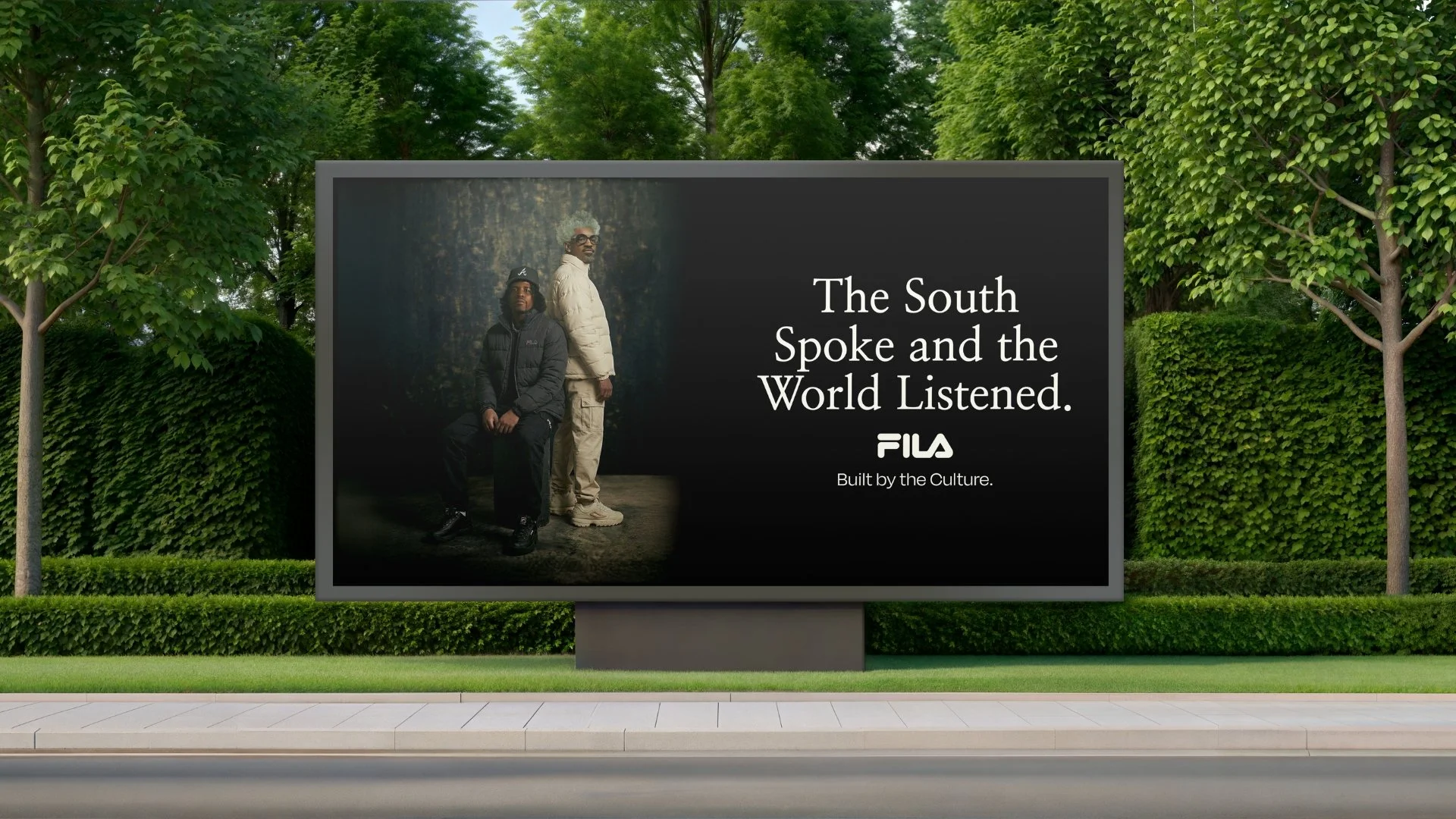 An outdoor billboard displays an advertisement with two men, one sitting and one standing, against a dark background with trees. The ad reads: 'The South Spoke and the World Listened. FILA Built by the Culture.'