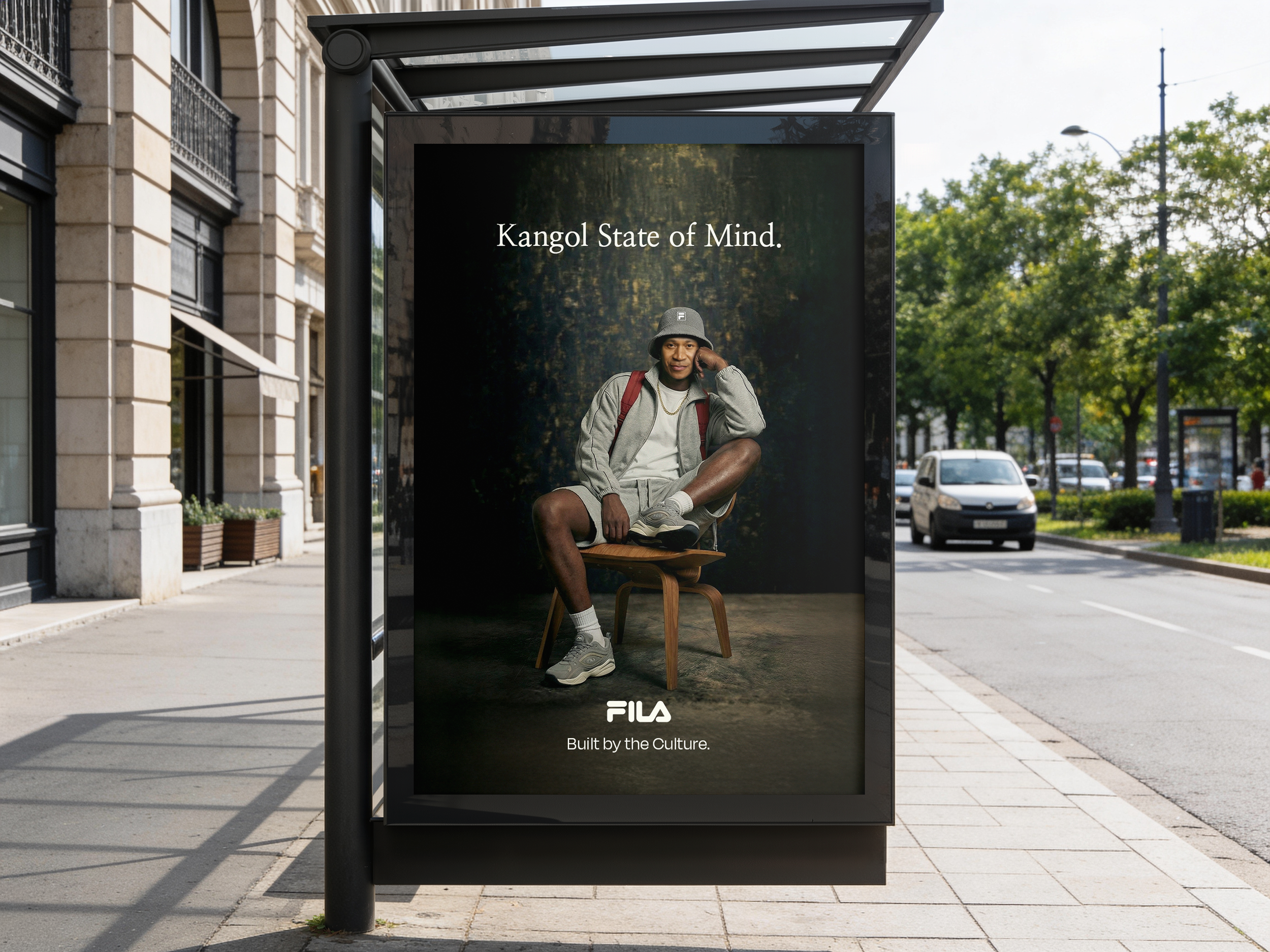 Advertisments at bus stop featuring a young woman in casual attire sitting on a chair with a forest background, captioned 'Kangol State of Mind,' and branding for Fila with the tagline 'Built by the Culture'.