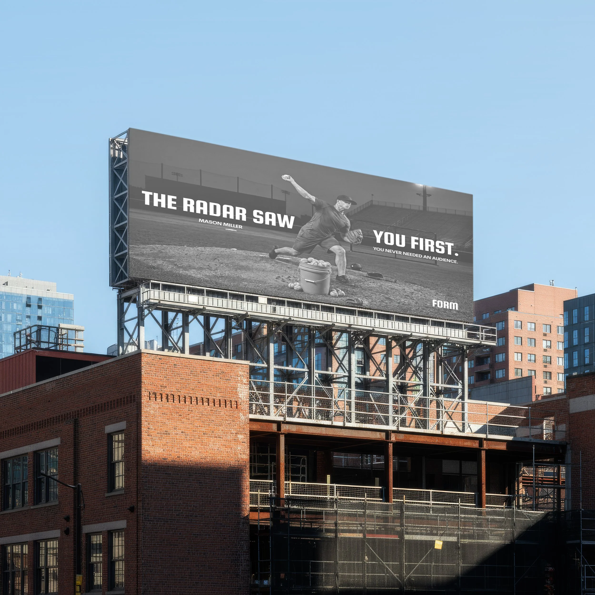 City building under construction with a billboard featuring a baseball player and inspirational quote, set against a clear blue sky.