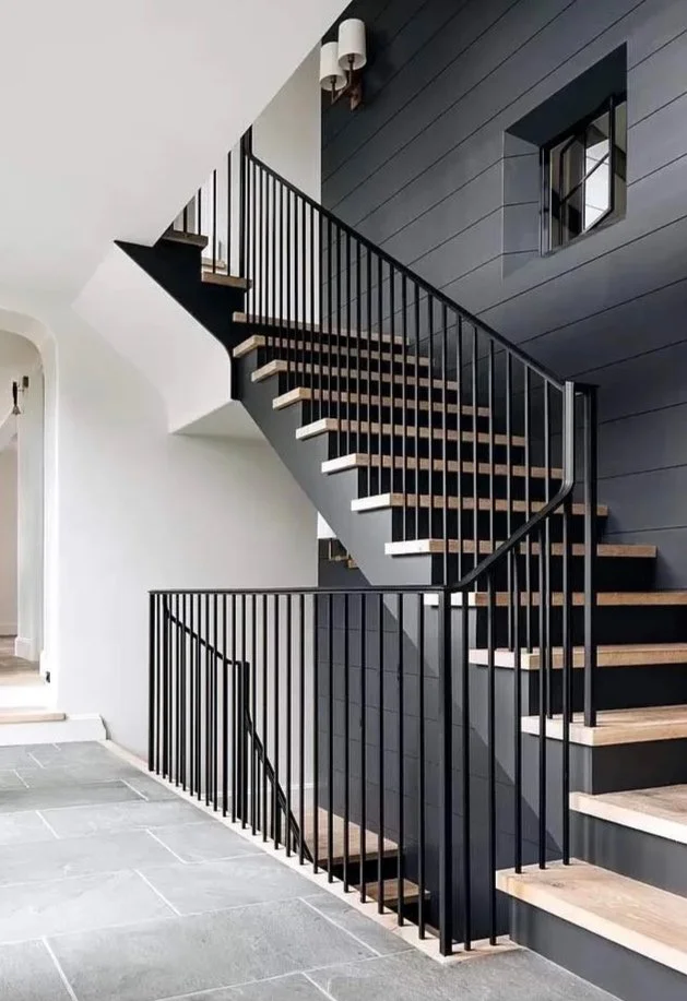 Modern staircase with black metal railing and wooden steps inside a contemporary home.