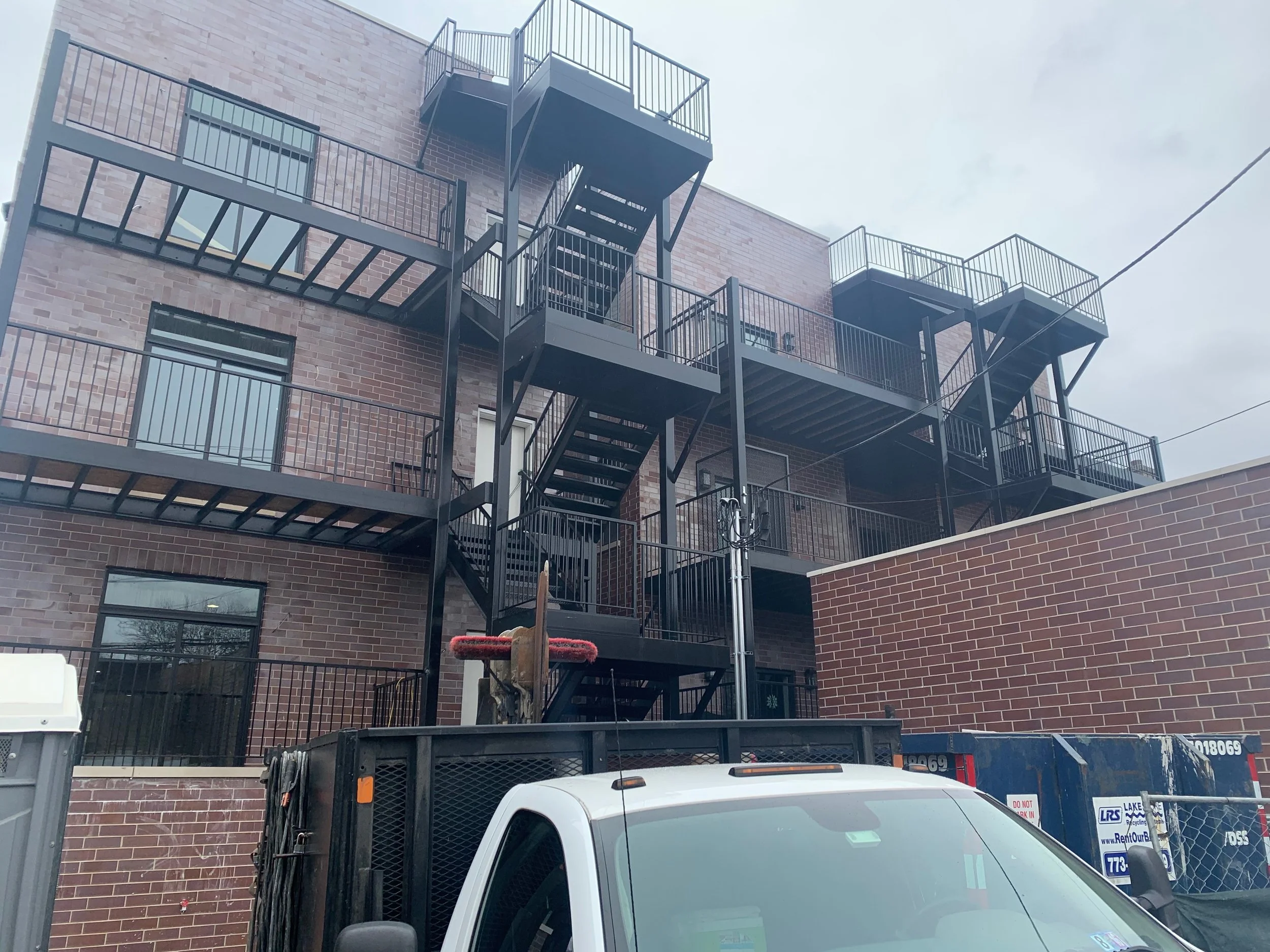 Black metal fire escape staircases and railings attached to a brick building.