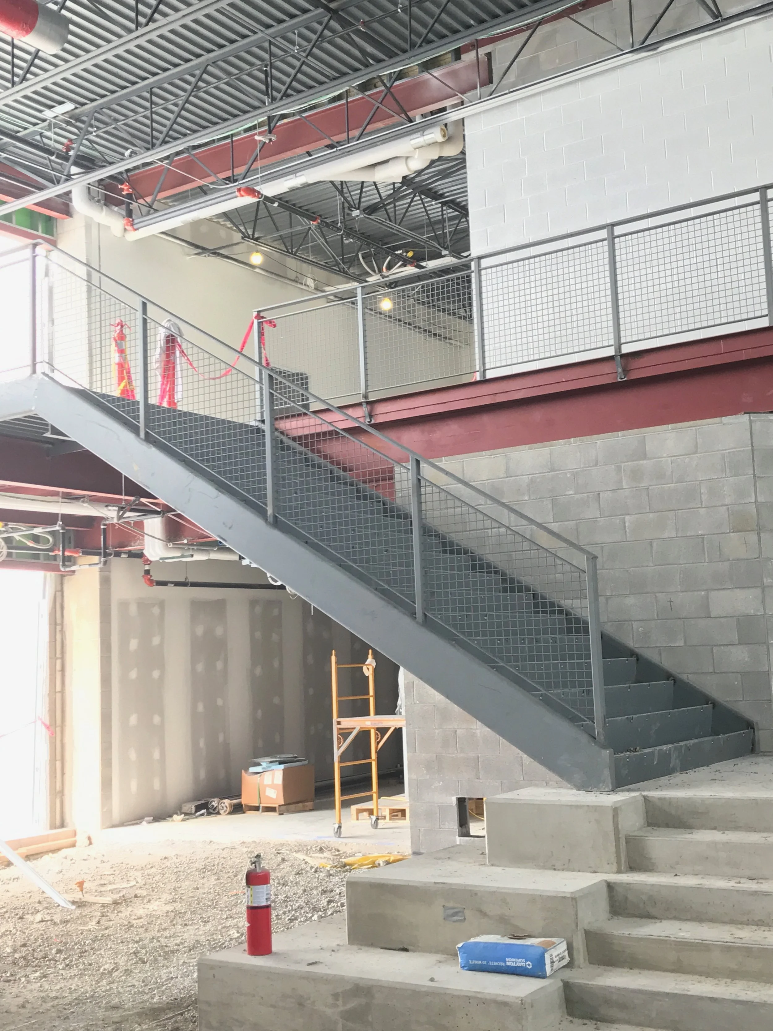 Construction site with concrete stairs, metal railing, and building framework under construction.