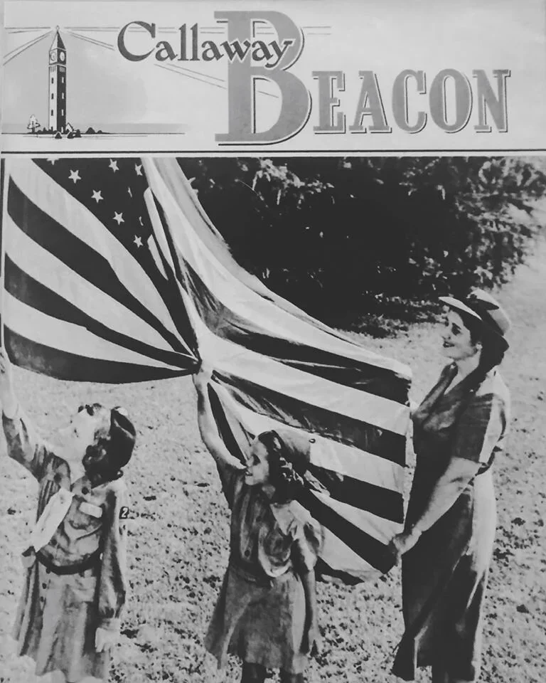 A historical black and white photograph of Boy Scouts and Girl Scouts holding a large American flag outdoors.