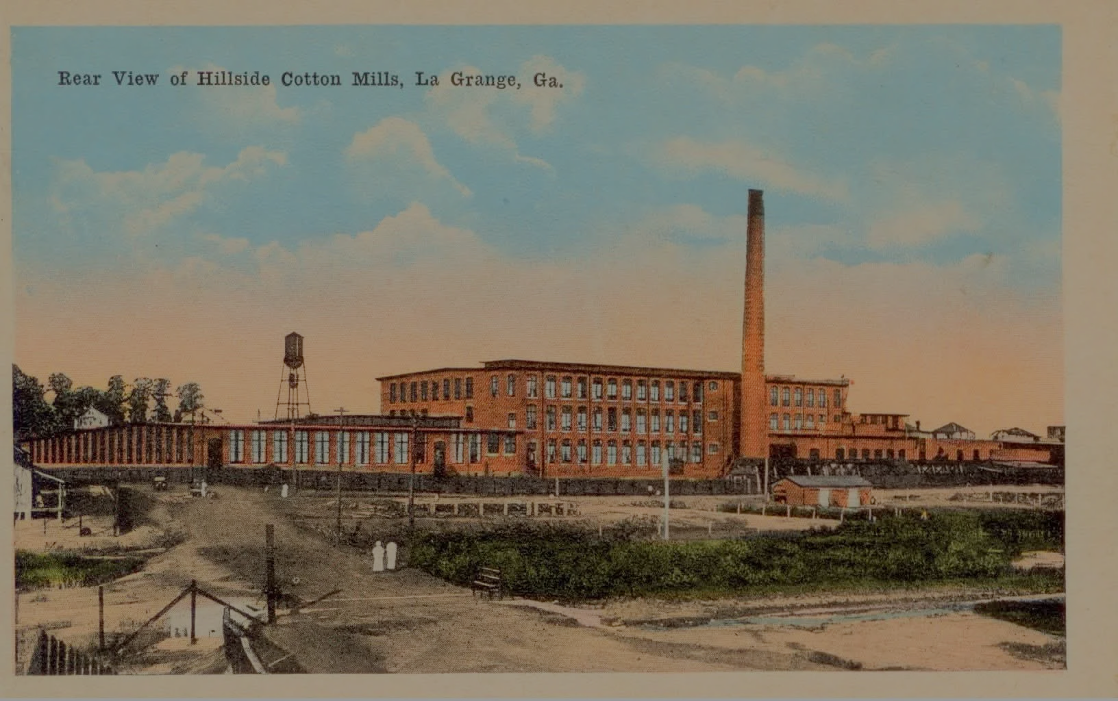 A historic photo of the Hillside Cotton Mills in LaGrange, Georgia, showing a large brick factory building with a tall chimney, a water tower, and surrounding area.