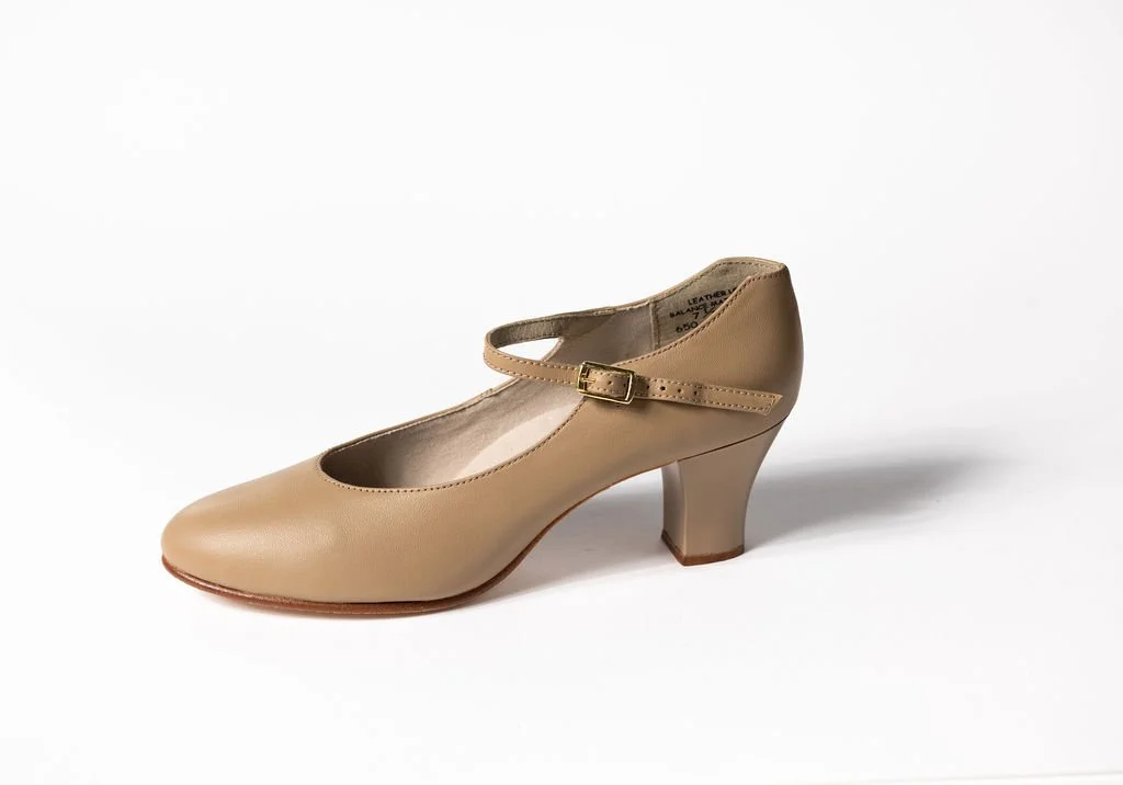 A caramel women's dress stage shoe with a strap and buckle, and a mid-height heel on a white background.
