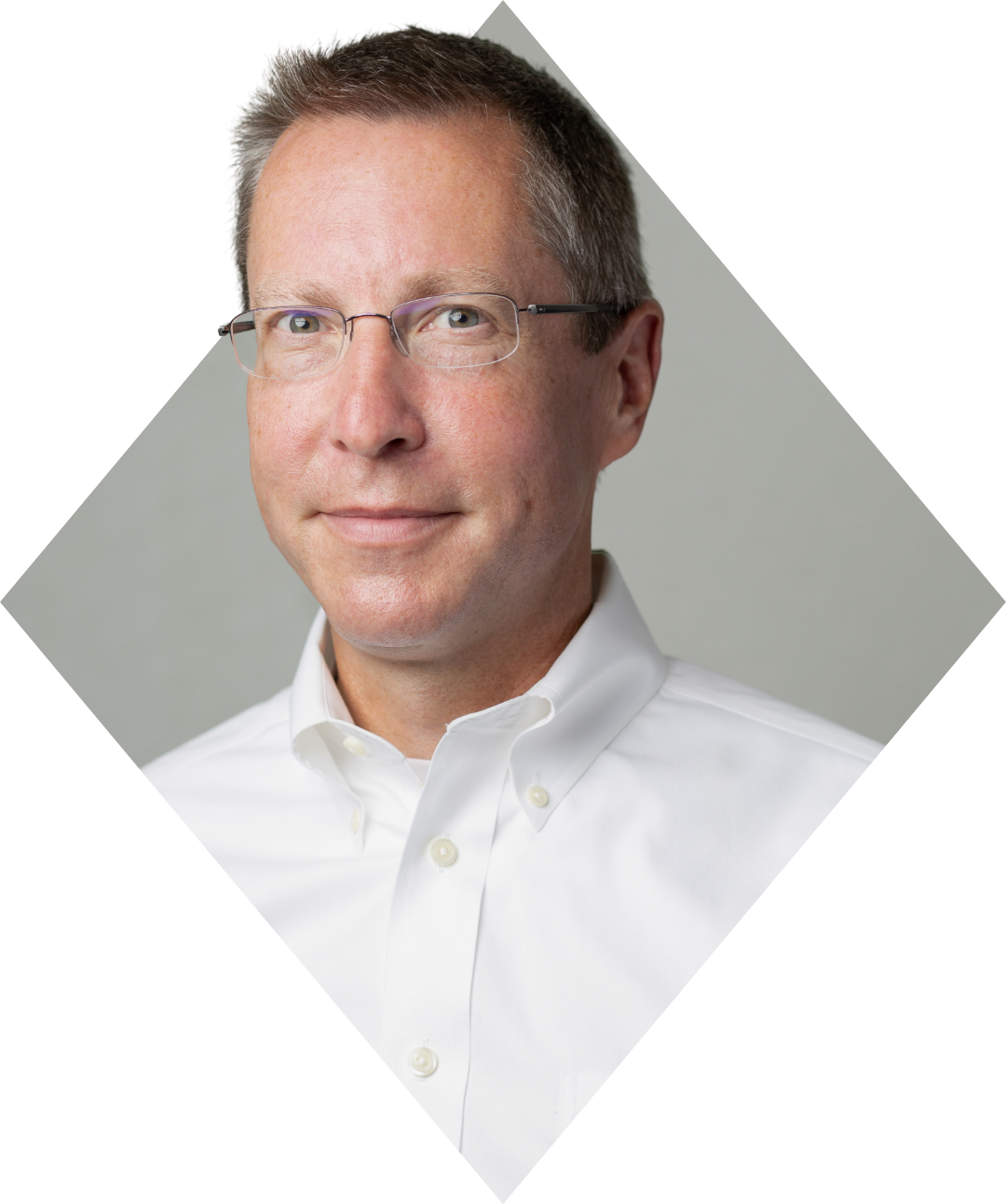 Headshot of a man with short brown hair and glasses, wearing a white button-down shirt, against a plain background.