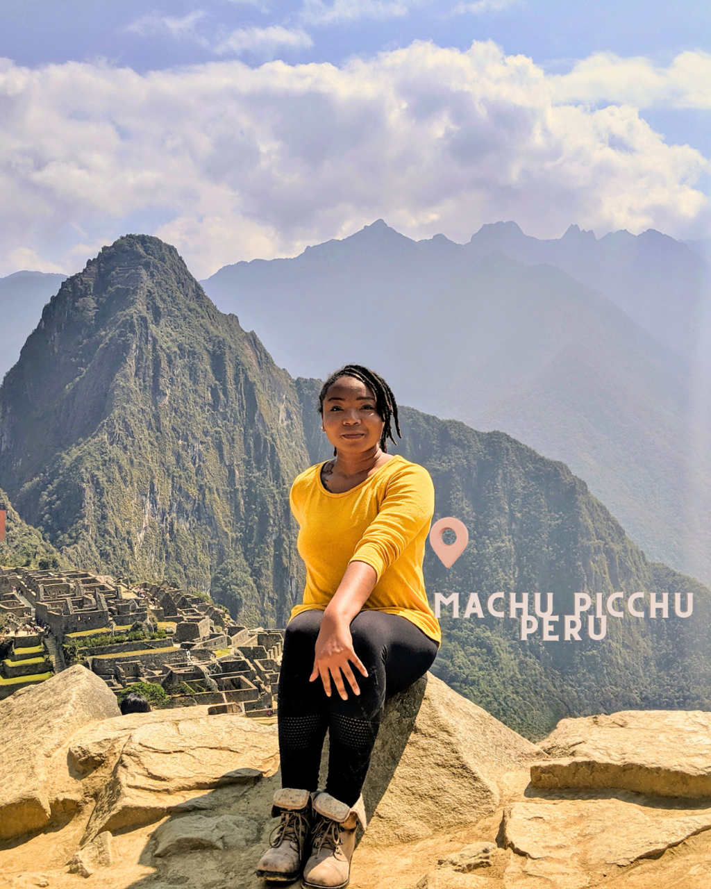 A woman in a yellow shirt sitting on rocks at Machu Picchu in Peru, with mountains and ancient ruins in the background.