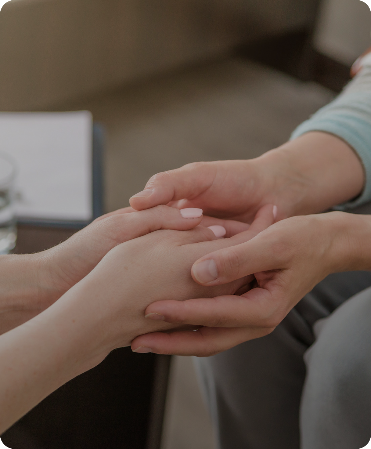 Close-up of two people holding hands, one person gently touching the other's hand.