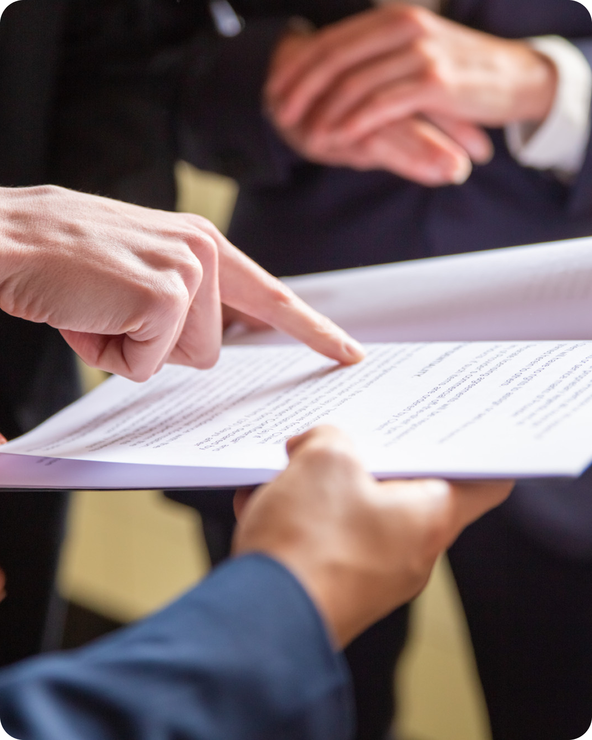 Close-up of people in formal attire discussing a document or legal paper, with one person pointing to the text.