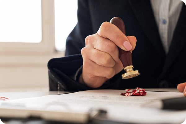A person in a dark suit using a stamp on a document.