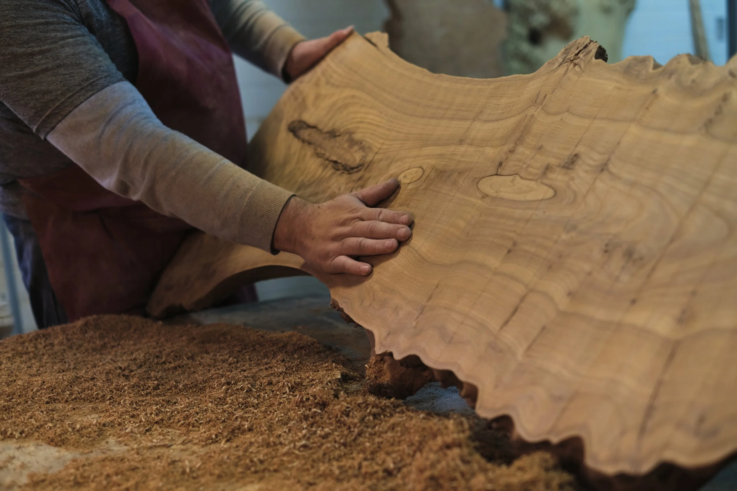 Person working with a large piece of wood, likely in woodworking or carpentry.