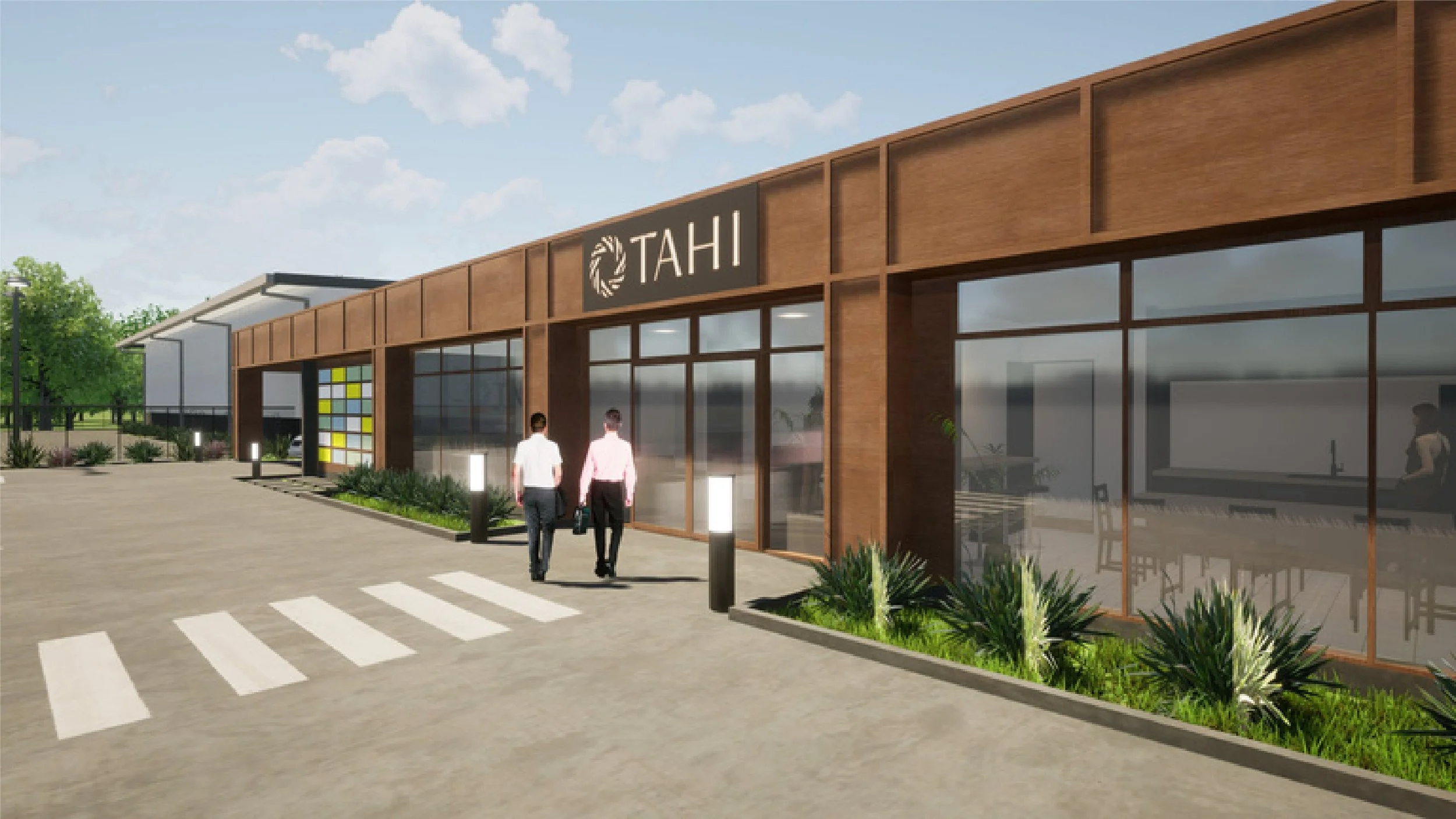 A modern building with a sign reading 'TAHI' and large glass windows. Two people are walking towards the entrance, and there is a crosswalk in front. The surroundings include plants, small trees, and decorative lighting.