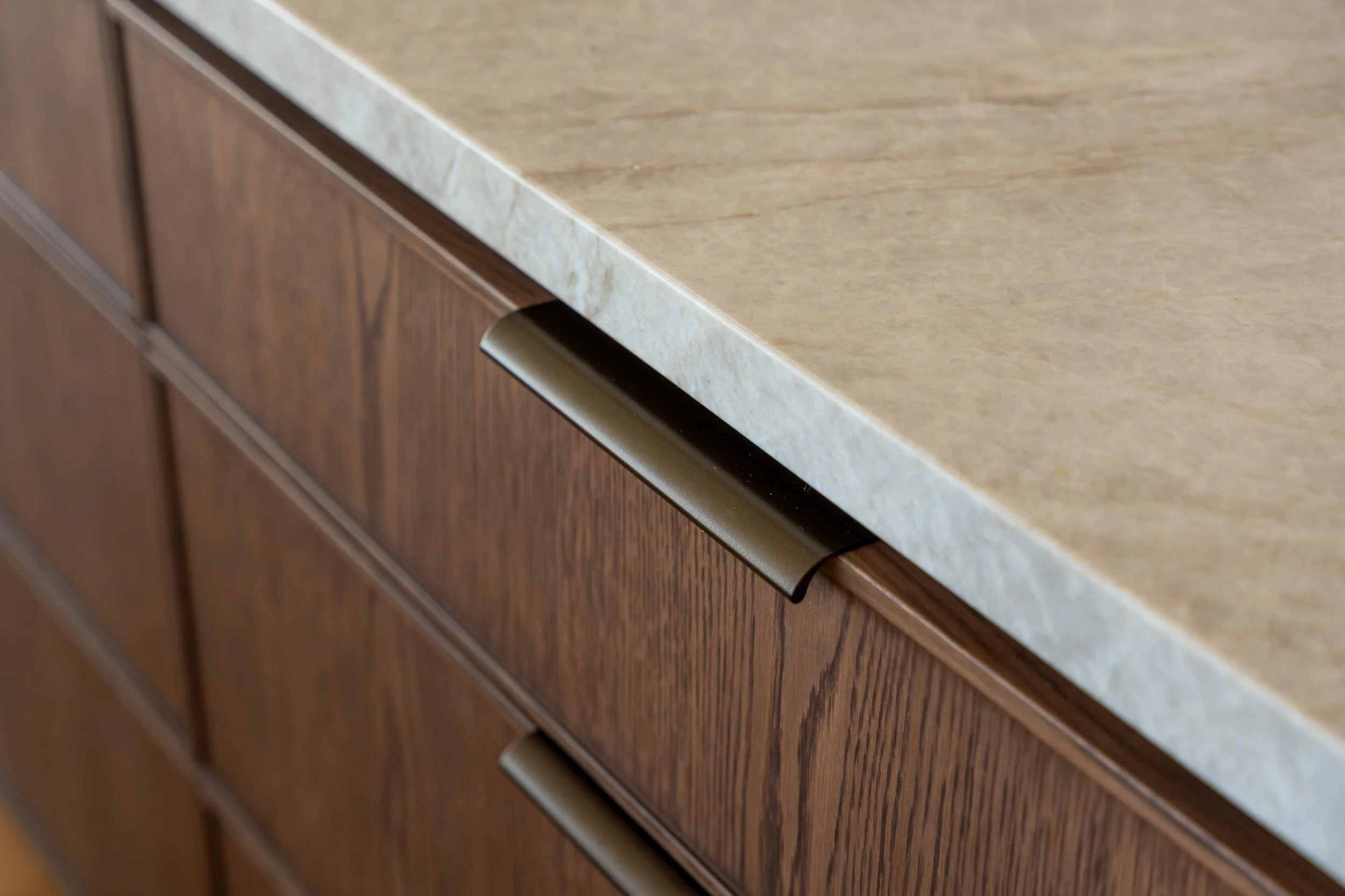 Close-up of a kitchen countertop and wooden cabinet drawers with a metallic handle.
