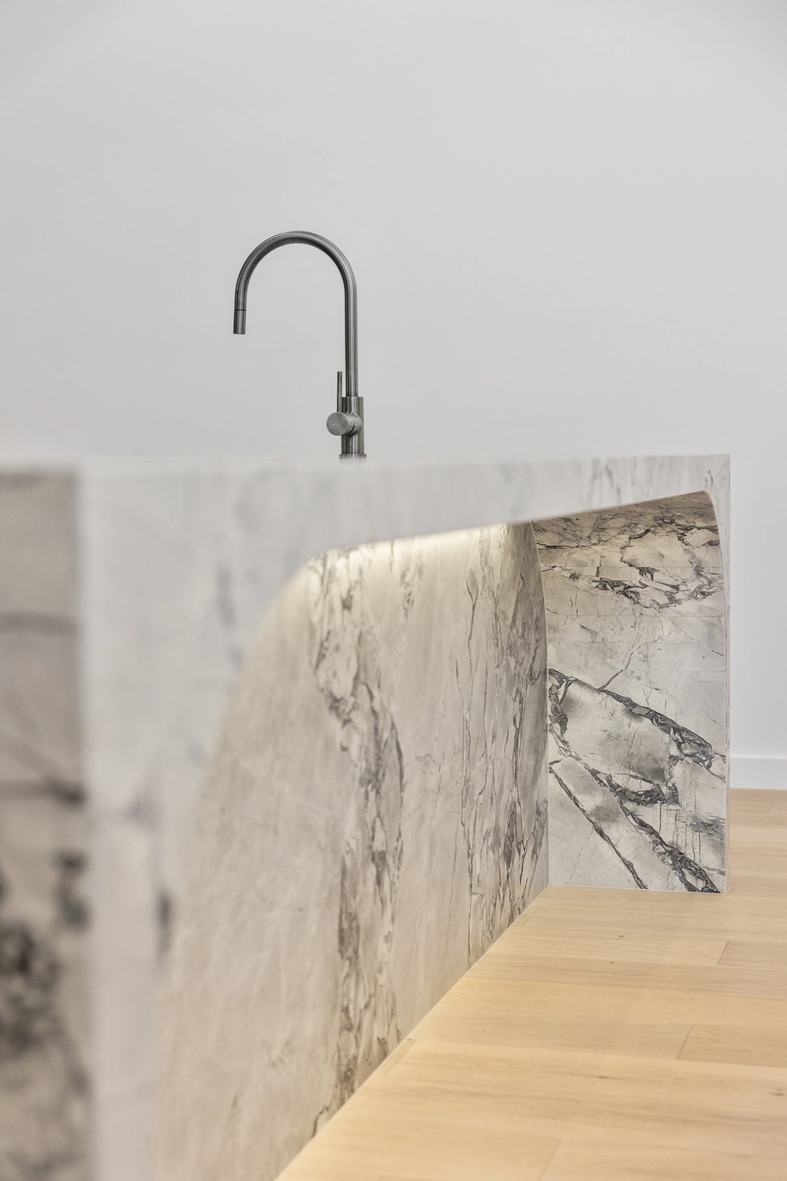 A modern kitchen sink with a stainless steel faucet, a marble countertop, and marble flooring.