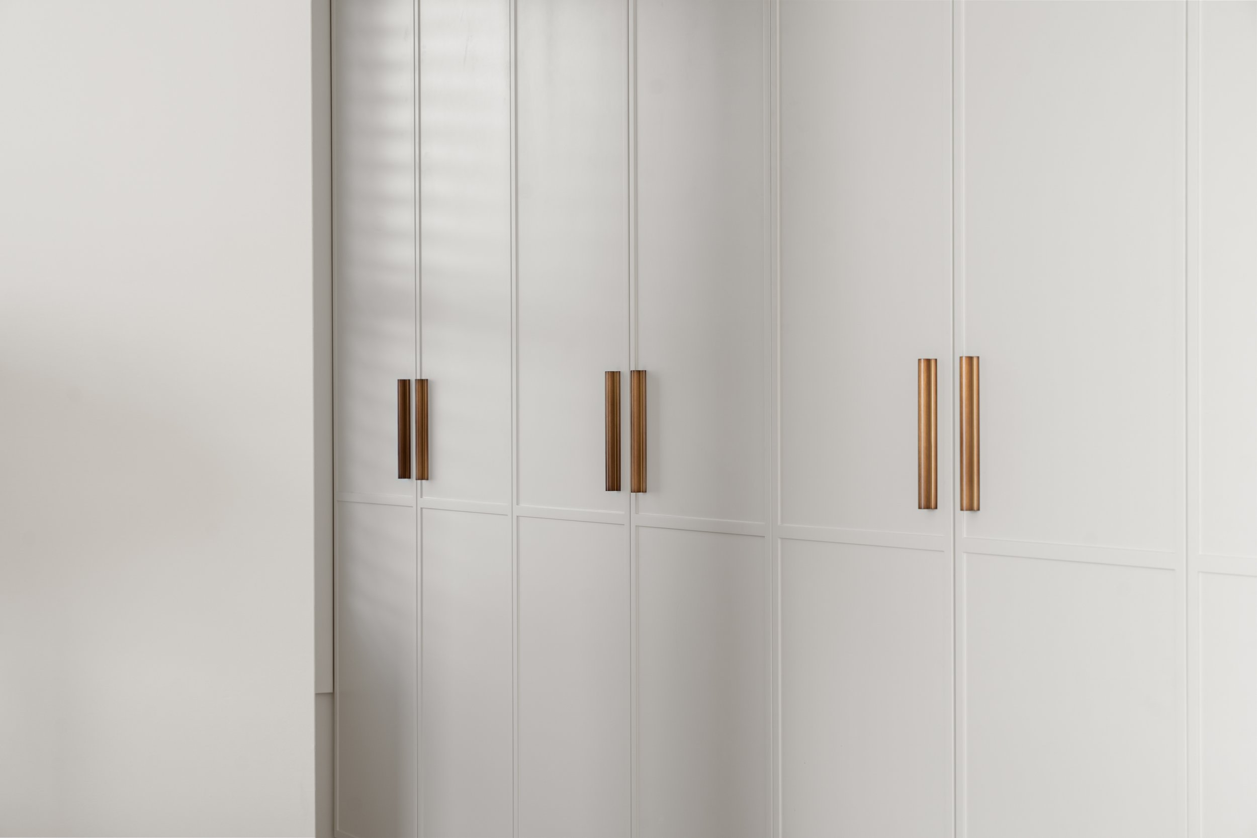 A white wardrobe with sliding doors and wooden handles.
