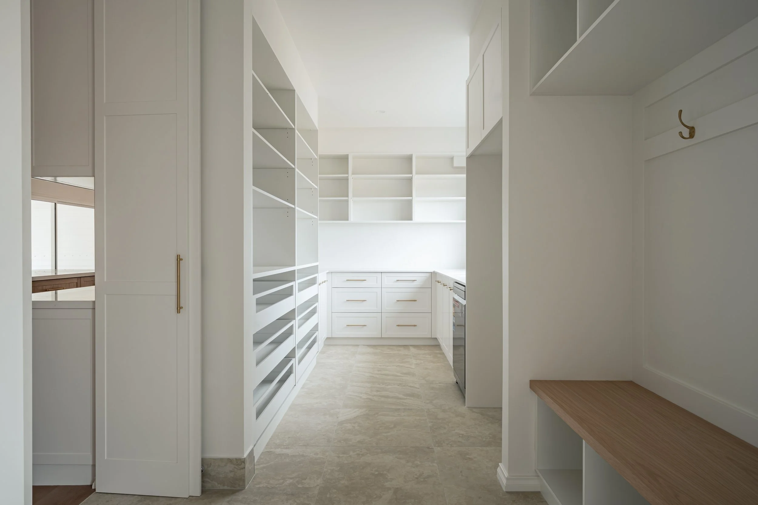 Empty white kitchen with open shelving, microwave, and tiled floor.