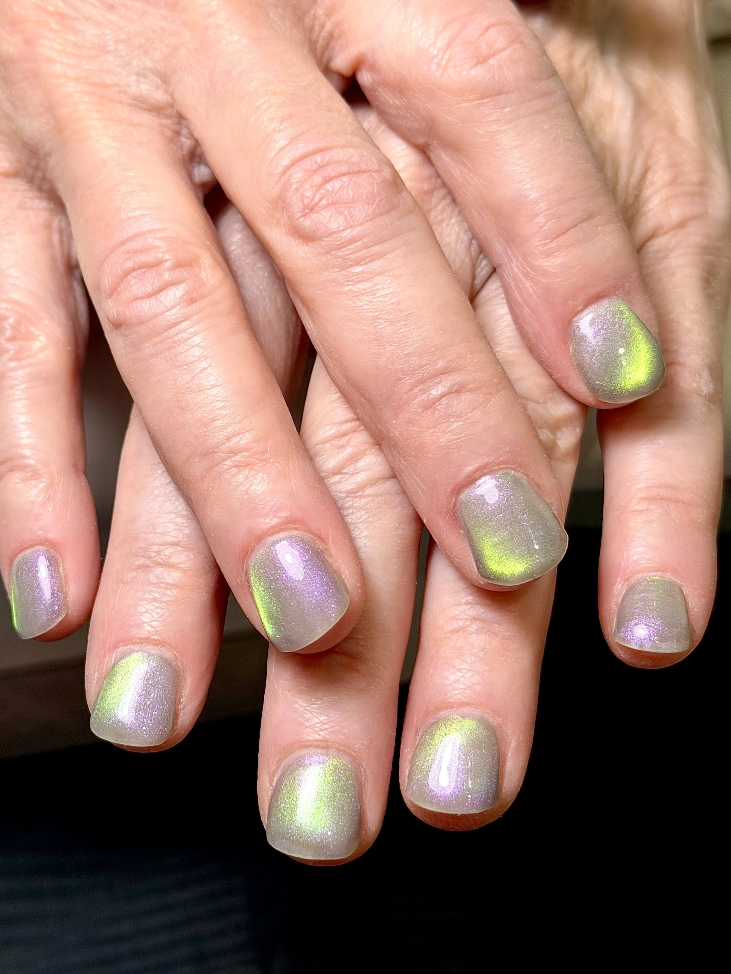close up of short square dual-shift purple to green cat-eye nails