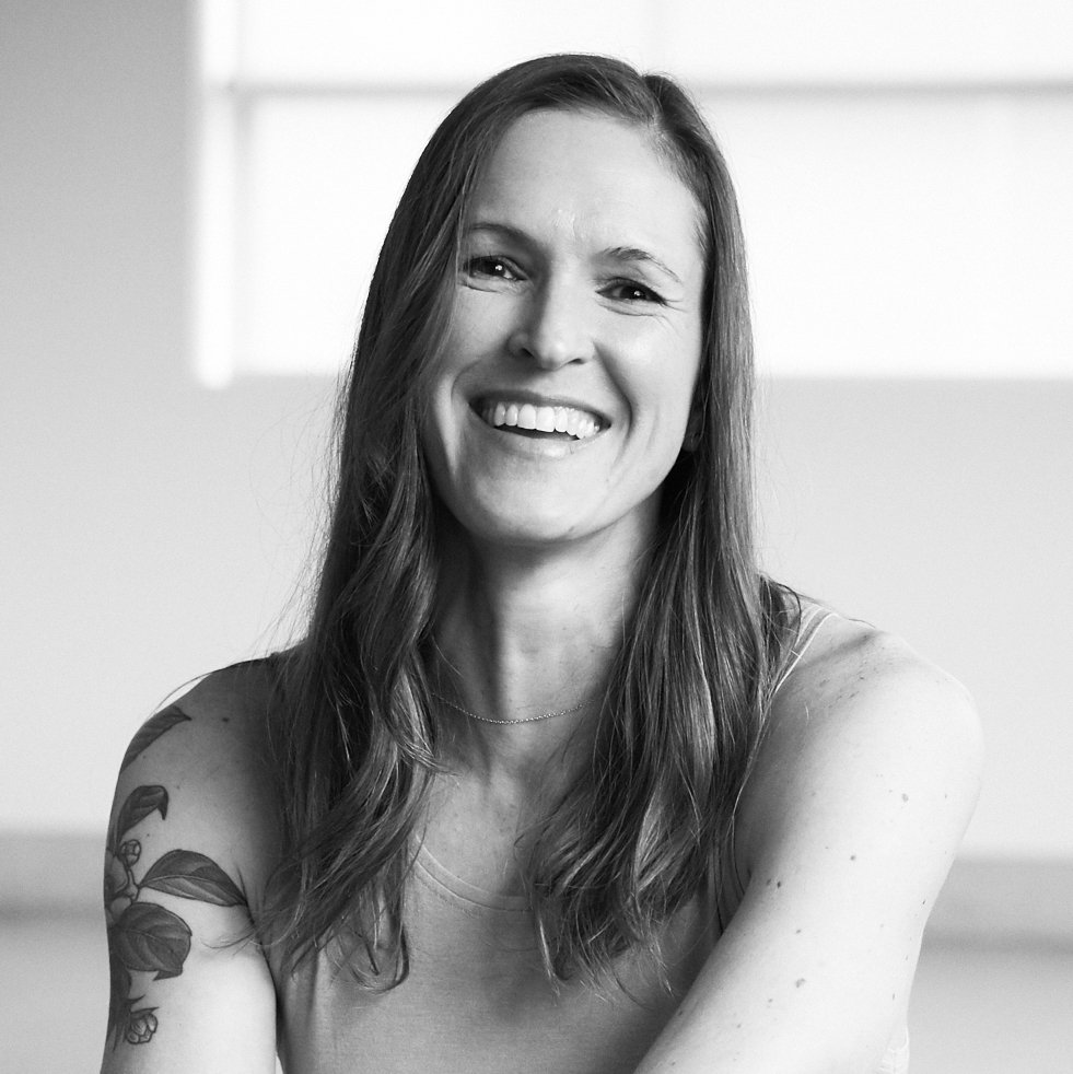 A woman with long hair smiling at the camera in black and white.