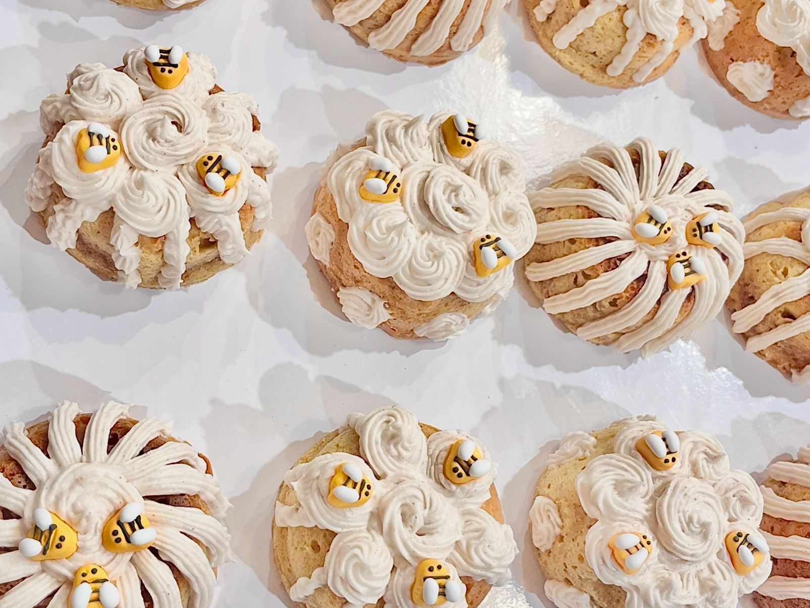 Cookies decorated with white icing and small bee-shaped decorations.