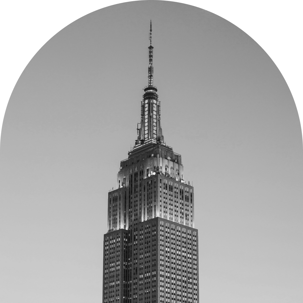 Black and white photo of the Empire State Building in New York City at night, lit up against a clear sky.