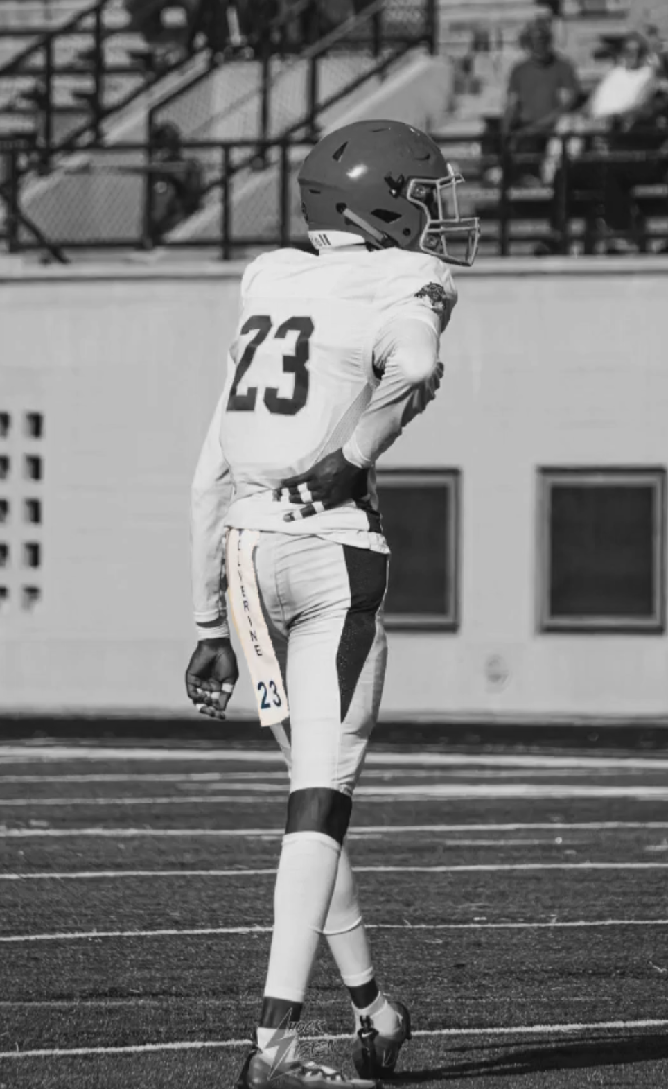 A football player wearing a helmet and uniform with the number 23 stands on the field during a game.
