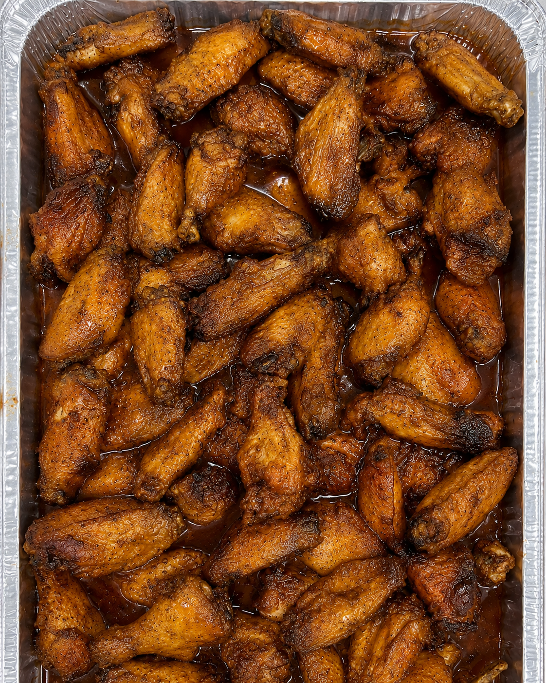 Tray of cooked chicken wings coated in a dark, glossy sauce.