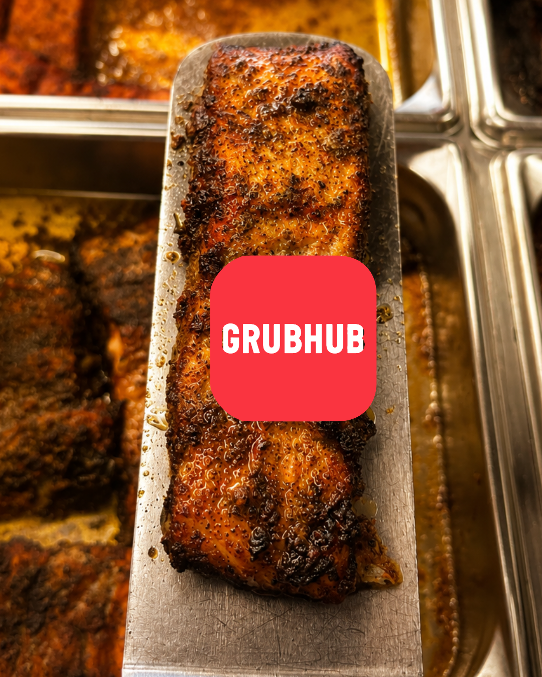 A tray of cooked spicy, seasoned chicken with a crispy, browned skin in a buffet setting.