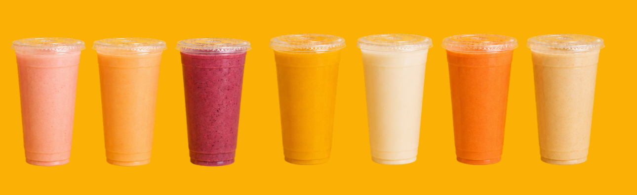 A row of eight colorful smoothies in clear plastic cups with lids, standing on an orange background.
