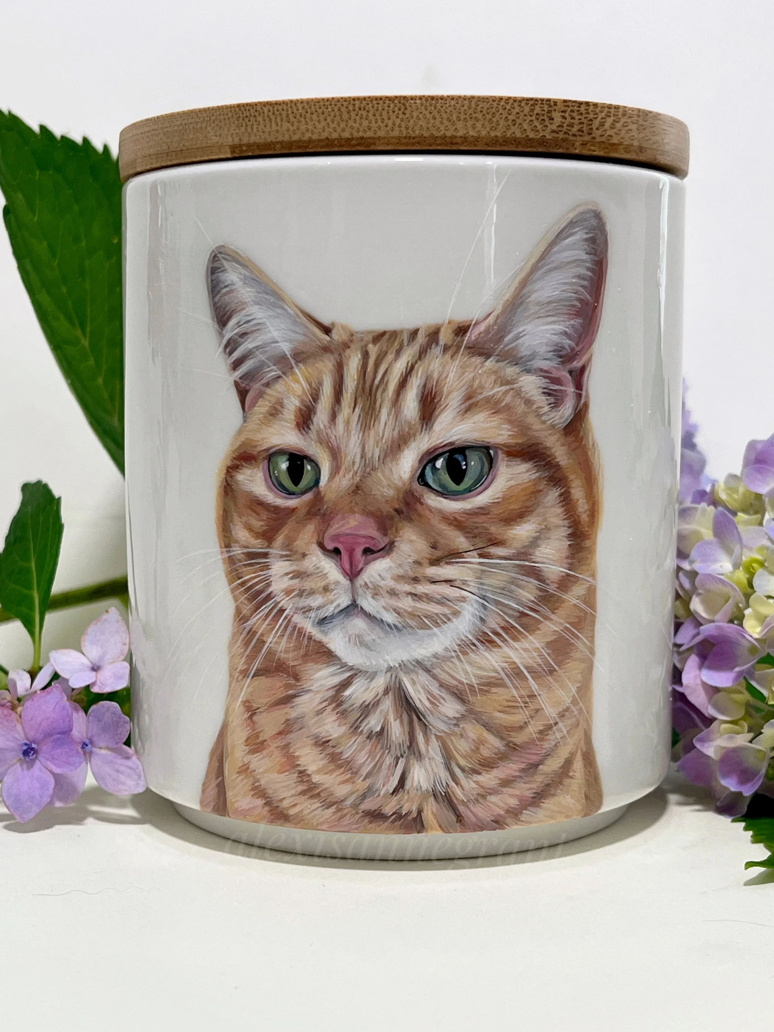 orange cat portrait urn hand painted from photo on ceramic jar with wood lid surrounded with real hydrangea
