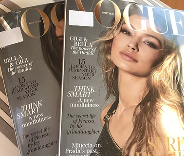 A magazine cover featuring a woman with long blonde hair, wearing a black top, with the word 'VOGUE' at the top. Headlines include Gigi & Bella, mindfulness, and the secret life of Picasso.