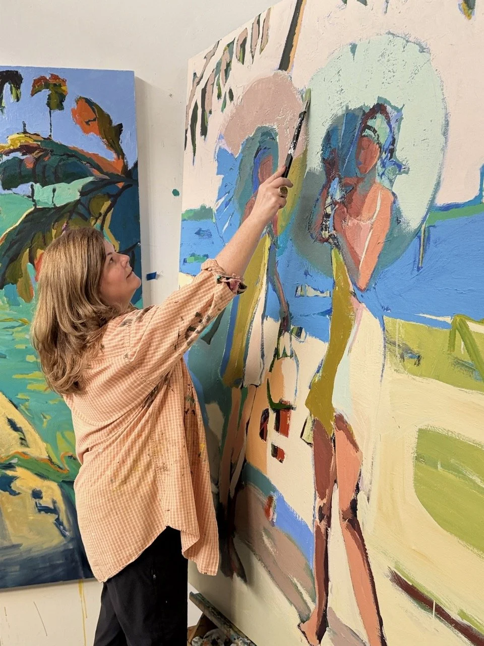 Woman painting a colorful abstract mural on a large canvas.