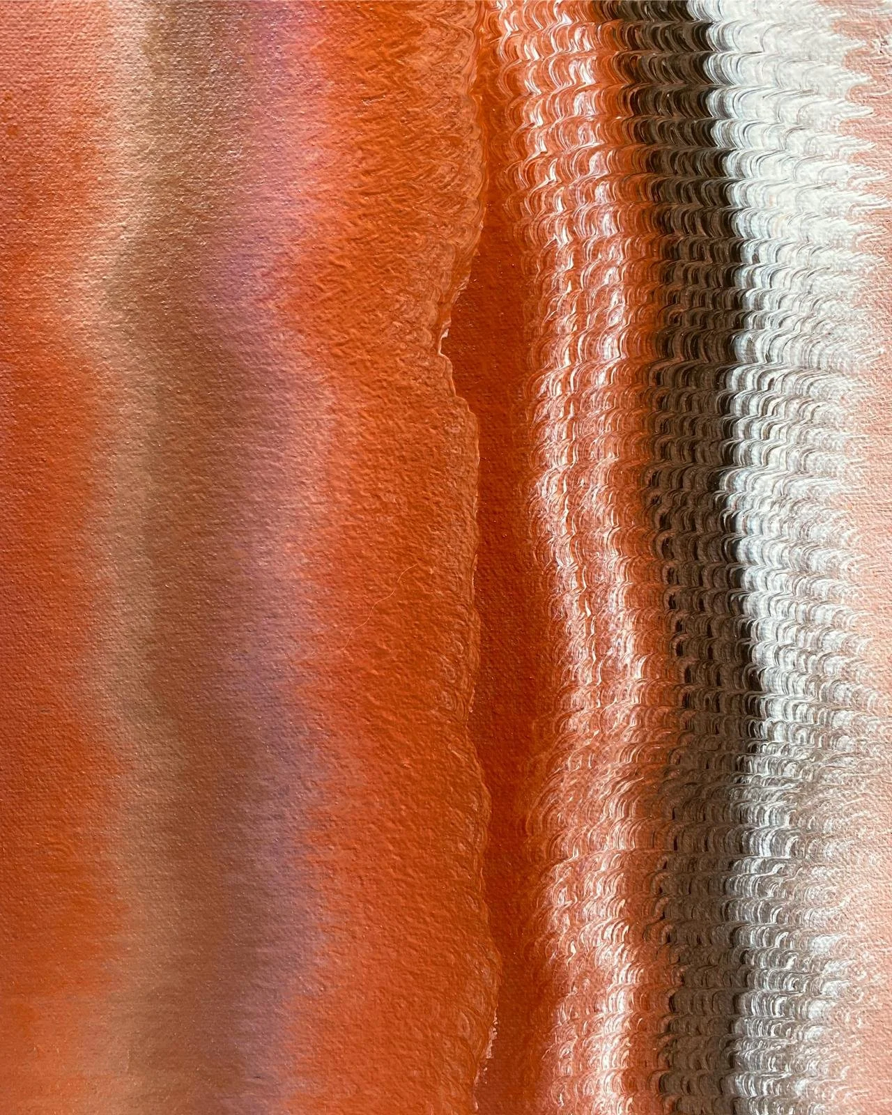 Close-up of a textured, metallic, patterned surface with shades of orange, black, white, and pink, creating an abstract design.
