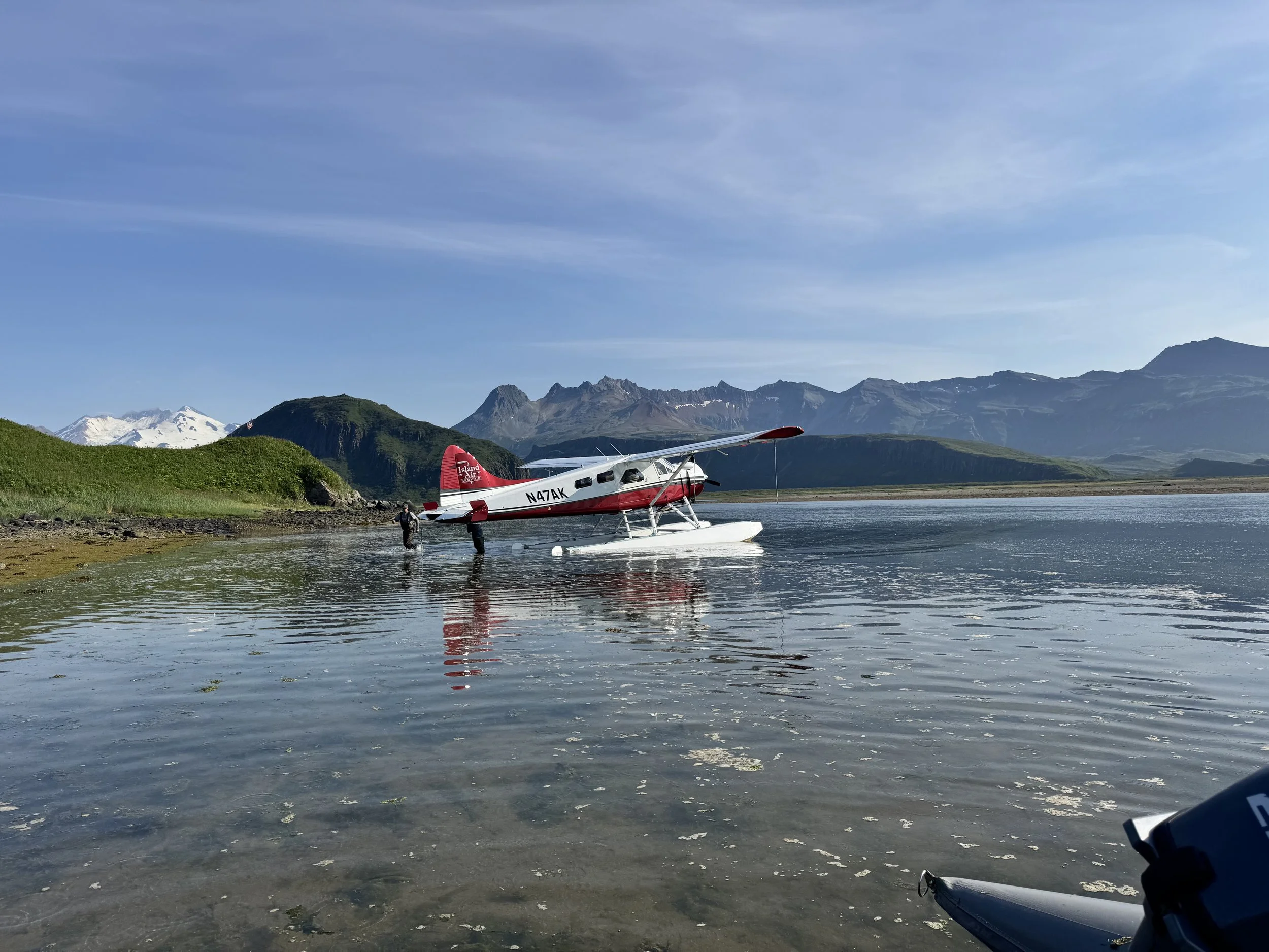 A seaplane on a body of water with mountainous landscape and clear sky in the background.