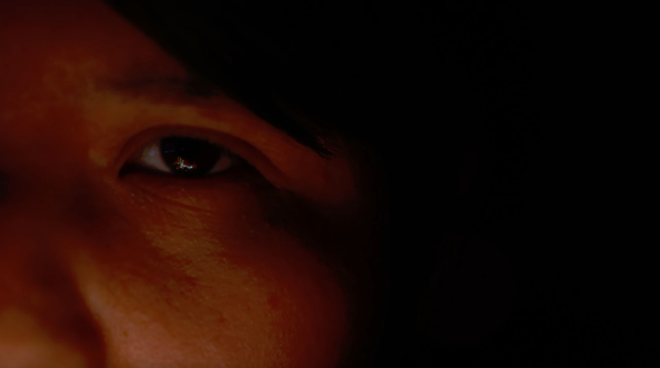 Close-up of Native American filmmaker SeaJay Justice, with a firelight reflection visible in their right eye.