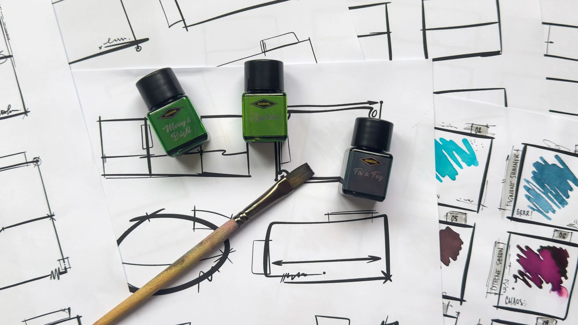 Desktop Nerd ink swatch sheet printables arranged with Diamine ink bottles and a brush.