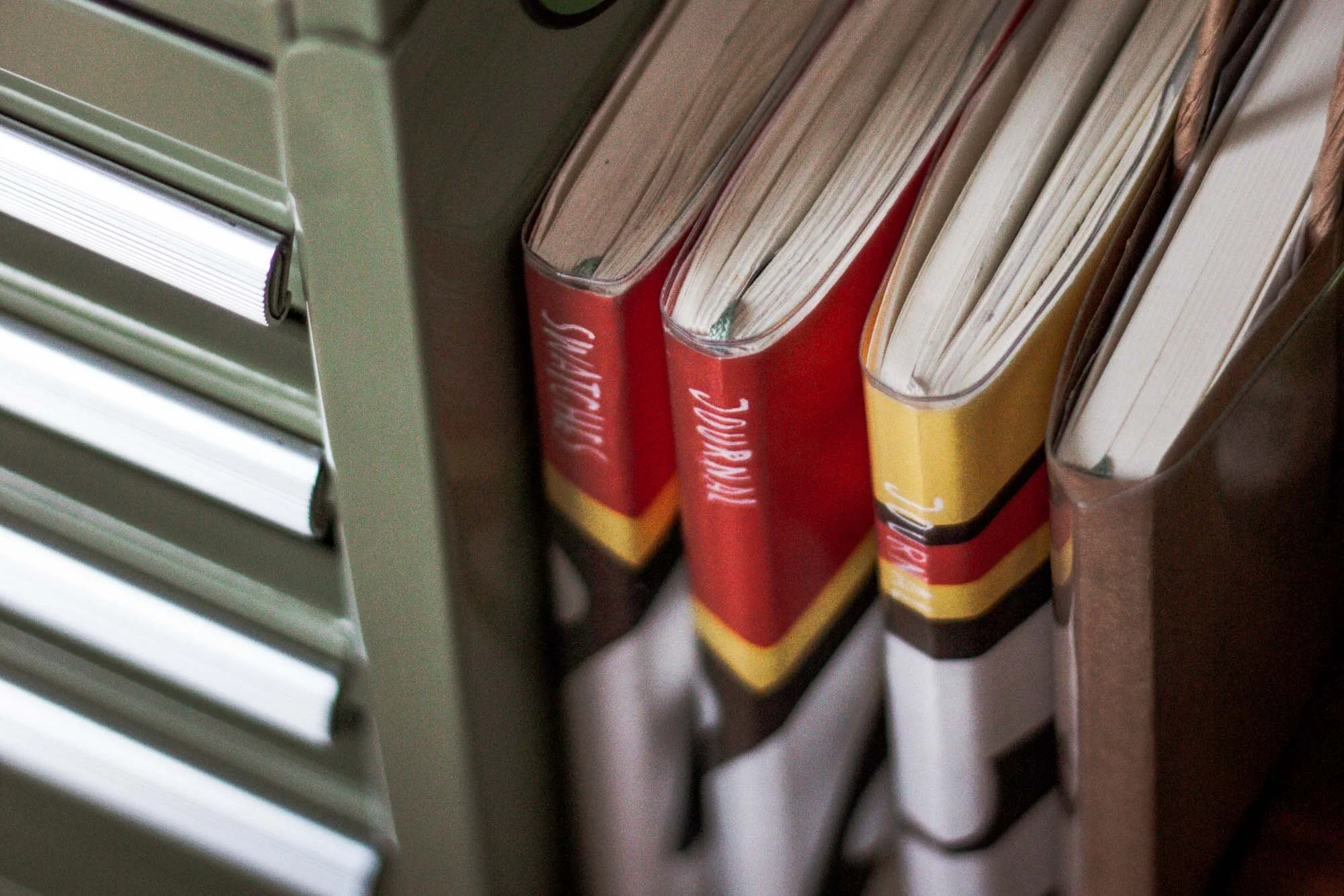 Pocket notebooks and journal inserts stacked beside a desk drawer, representing the tension between collecting notebooks and using them.